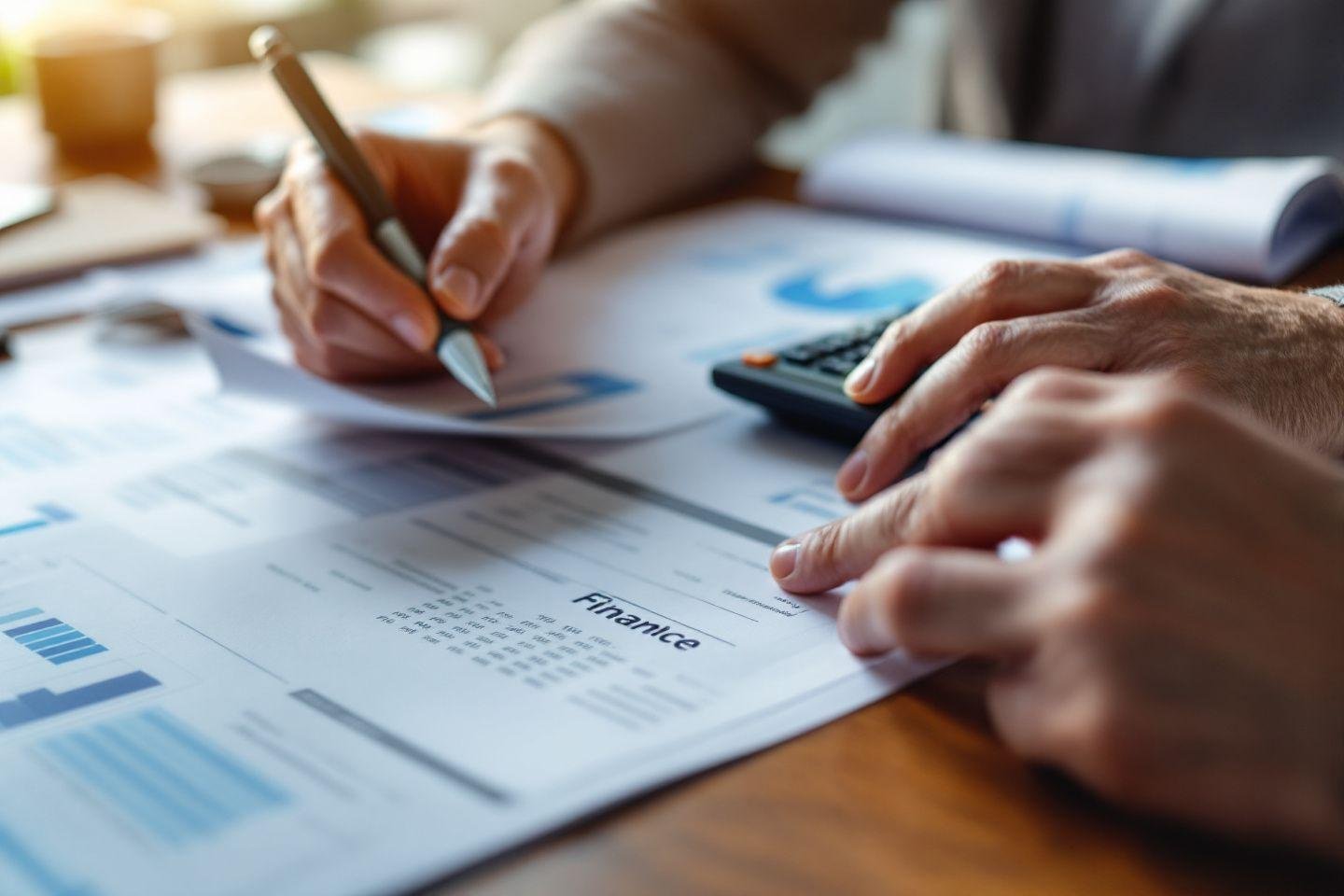 Mains travaillant sur des documents financiers avec calculatrice